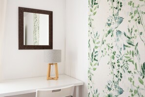 A white vanity with a wooden stool, a mirror with a dark frame, and a lamp with a textured lampshade. - Sierra Nevada Views | Sunny, Spacious & Renovated (Granada)