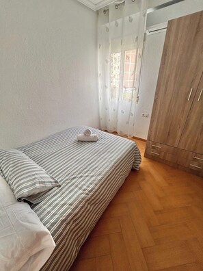 A bedroom with a bed, a wardrobe, and a window with curtains. - Impresionante Puente Romano de Córdoba & Parking (Cordoba)