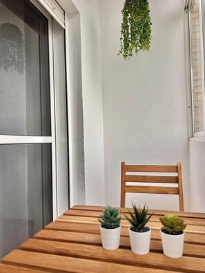 A wooden table with three potted plants, a wooden chair, and a hanging plant against a textured wall. - Impresionante Puente Romano de Córdoba & Parking (Cordoba)