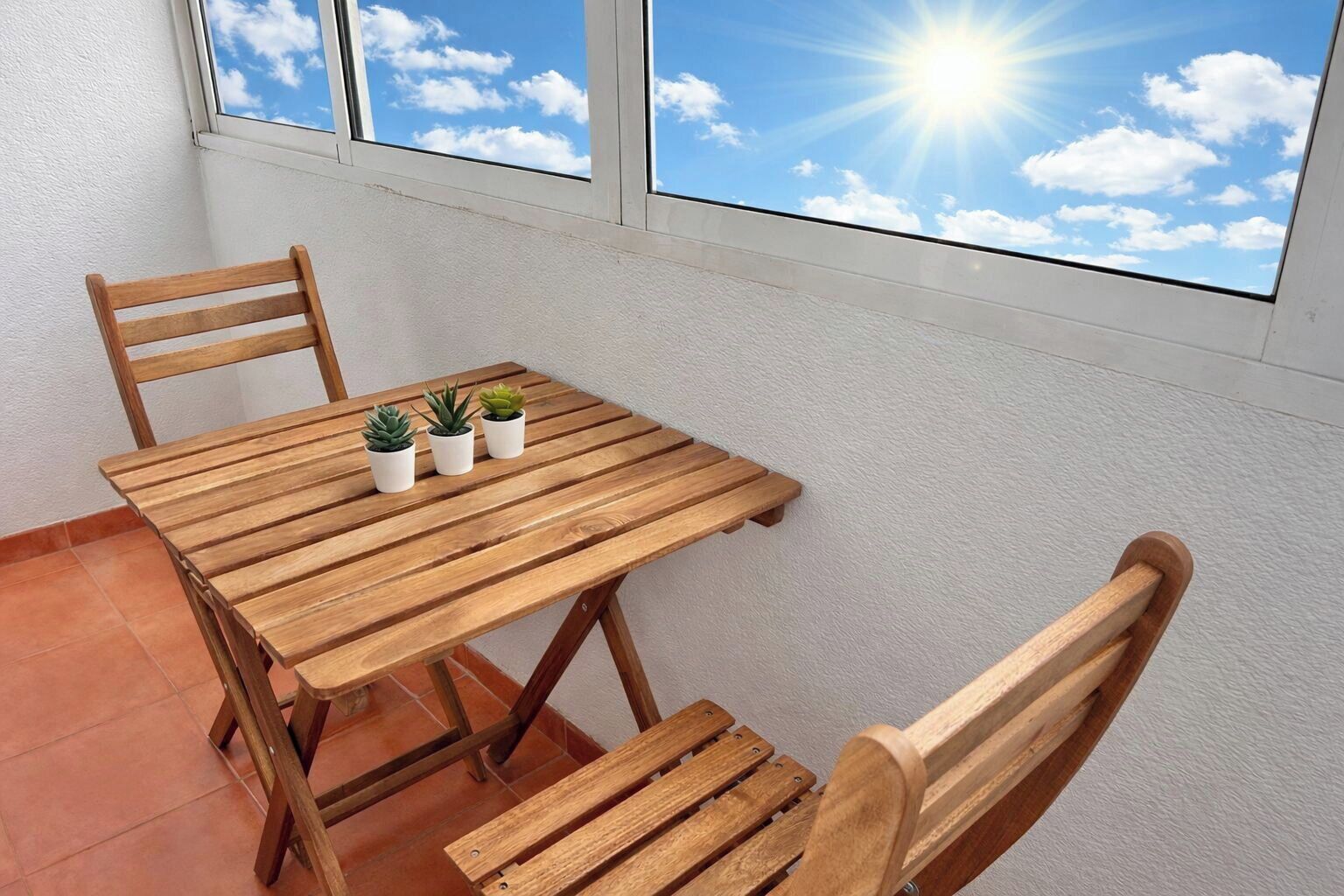 Una mesa de madera con tres plantas en macetas y dos sillas en una habitación con vista al cielo a través de una ventana.