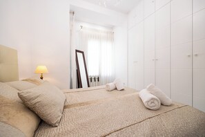 Una habitación de hotel con una cama, una lámpara de noche, un espejo y un armario.