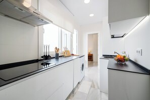 A modern kitchen with a central island, a built-in oven, and a sink with a fruit bowl. - El Patio interior de Alfonso XIII (Cordoba)