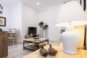 Ein modernes Wohnzimmer mit einem Holzespeisetisch, einer weißen Lampe und einem Fernseher.