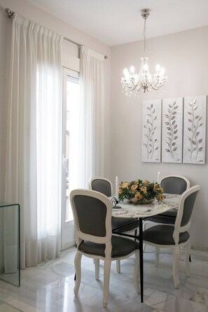 A dining area with a table set for four, surrounded by chairs, a chandelier, and wall art. - La terraza de Alfonso XIII (Cordoba)