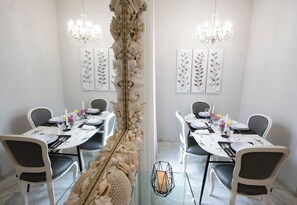 A dining area with a central decorative column, white walls, and chandeliers. - La terraza de Alfonso XIII (Cordoba)