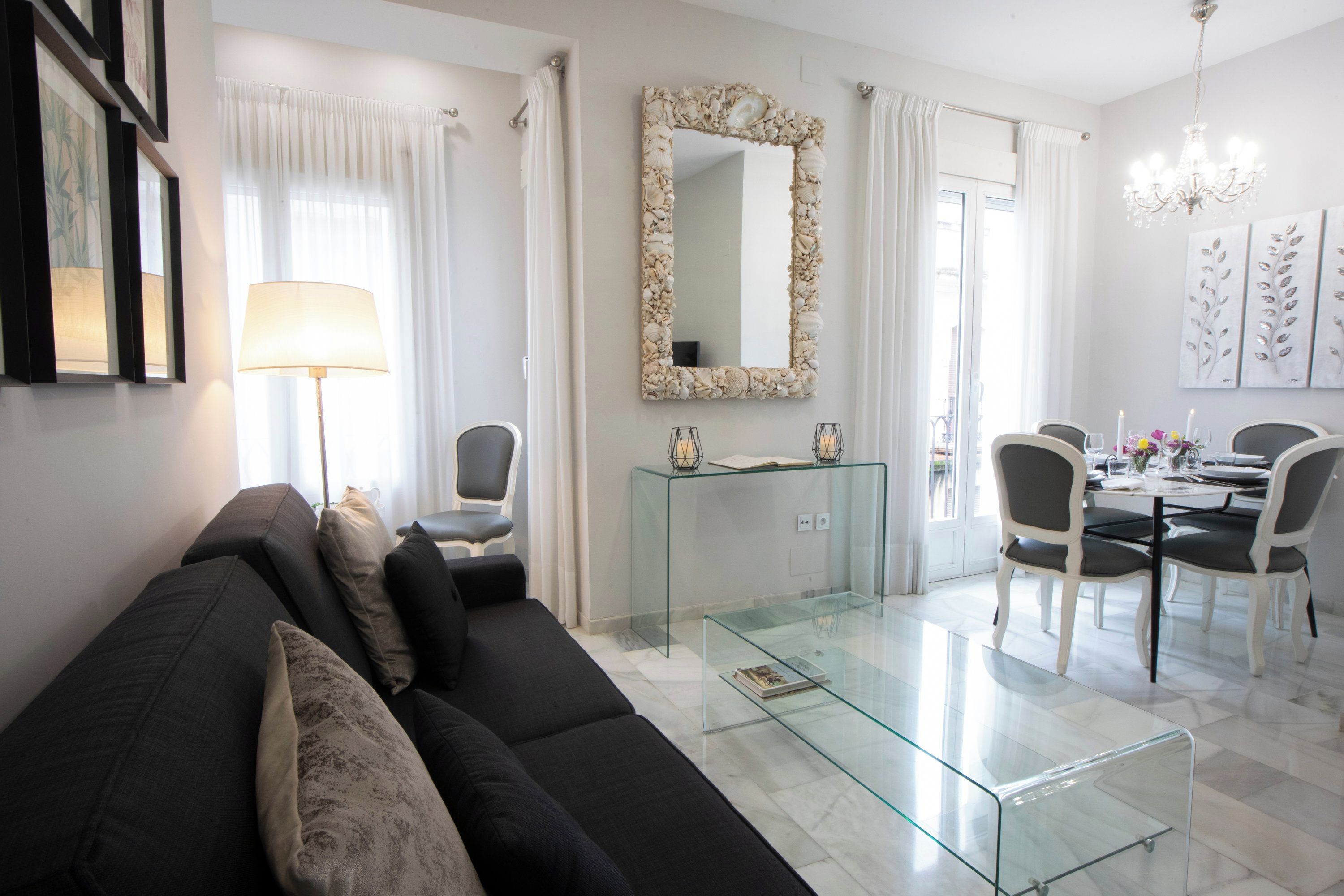Un salon moderne avec une table basse en verre, un canapé et un coin repas comprenant des chaises et une table.