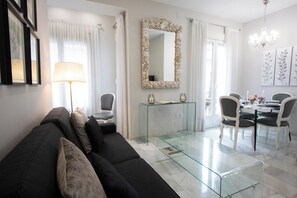 A modern living room with a glass coffee table, a sofa, and a dining area with chairs and a table. - La terraza de Alfonso XIII (Cordoba)