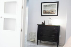 Ein Flur mit einem schwarzen Kommode, einem gerahmten Bild an der Wand und einer Tür zu einem anderen Zimmer.
