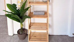 Ein Holzregal mit Gläsern, klaren Bechern und einem gestreiften Tuch.
