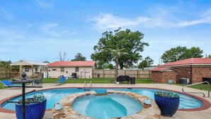 A backyard with a swimming pool, lounge chairs, a barbecue area, and a brick building. - The Plash Pad - 4-bedroom w/Pool in Gulf Shores!! Your Vacation Destination!! (Gulf Shores)