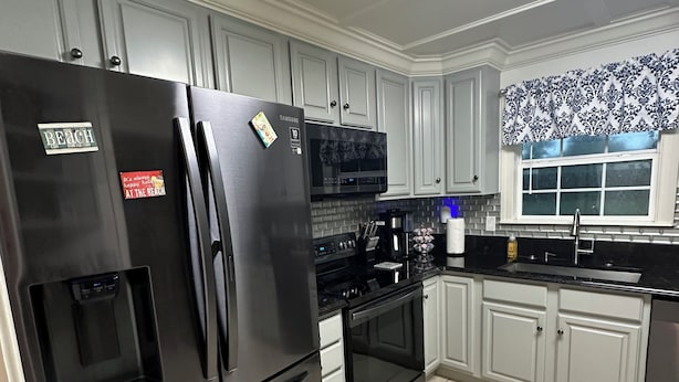 A modern kitchen with stainless steel appliances, white cabinetry, and a tiled floor. - The Plash Pad - 4-bedroom w/Pool in Gulf Shores!! Your Vacation Destination!! (Gulf Shores)