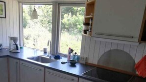 Une cuisine avec une fenêtre, des meubles blancs, un évier et un plan de travail.