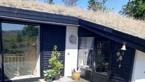 Une maison moderne avec un toit en pente, une terrasse en bois et des plantes en pot.