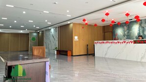 A hotel reception area with a marble reception desk, wooden paneling, and red lanterns on the ceiling.