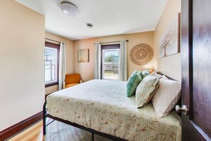 A bedroom with a bed, a chair, a window, and a door. - The Mystic Inn | Wine and Cheese Shop Downstairs | Downtown LG (Lake Geneva)