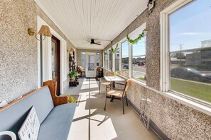 A sunlit interior with a ceiling fan, a sofa, tables, chairs, and a view of the outside. - The Mystic Inn | Wine and Cheese Shop Downstairs | Downtown LG (Lake Geneva)
