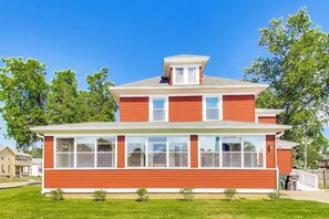 A two-story house with a red exterior, large windows, and a small porch. - The Mystic Inn | Wine and Cheese Shop Downstairs | Downtown LG (Lake Geneva)
