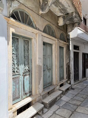 A building with arched windows and a stone staircase leading to the entrance. - Cosy Rooms in a Traditional House in the 'Marble Village' on the Island of Naxos (Naxos)