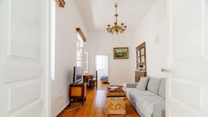 A living room with a wooden floor, a sofa, a television, a wooden cabinet, and a chandelier. - Cosy Rooms in a Traditional House in the 'Marble Village' on the Island of Naxos (Naxos)