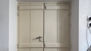 A white double door with a handle and a lock, a small framed picture above it, and a power outlet to the right. - Cosy Rooms in a Traditional House in the 'Marble Village' on the Island of Naxos (Naxos)
