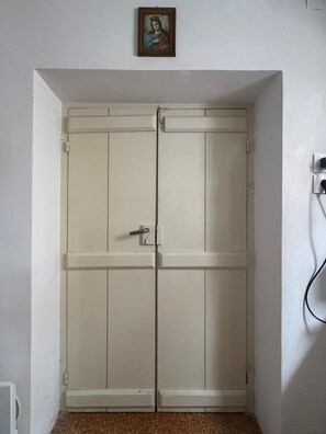 A white double door with a handle and a lock, a small framed picture above it, and a power outlet to the right. - Cosy Rooms in a Traditional House in the 'Marble Village' on the Island of Naxos (Naxos)