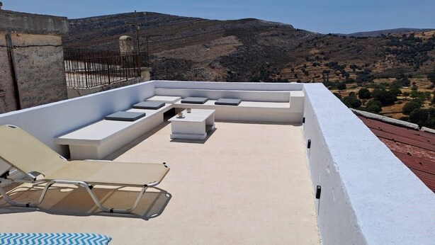 A rooftop terrace with lounge chairs, a small table, and a view of a hilly landscape. - Cosy Rooms in a Traditional House in the 'Marble Village' on the Island of Naxos (Naxos)