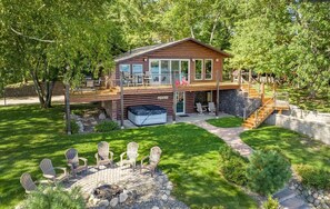 Eine Hütte mit einer Terrasse, Sitzgelegenheiten im Freien und einem Whirlpool.