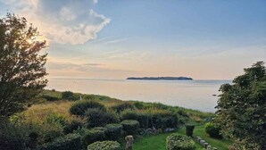 A coastal landscape with a grassy area, neatly trimmed bushes, and a view of the sea. - 4 Star Holiday Home in Follenslev (Follenslev)