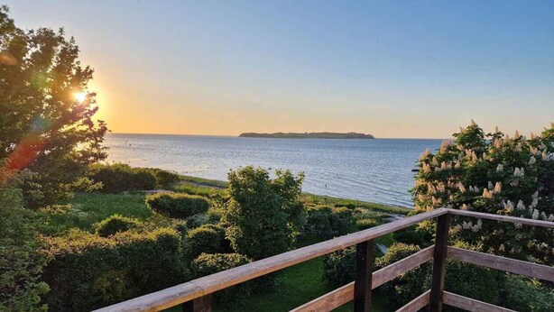 A wooden deck with a view of the sea and a distant island. - 4 Star Holiday Home in Follenslev (Follenslev)