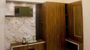 A room with a ceiling fan, recessed lighting, a built-in TV, wooden cabinets, and a marble floor. - Shiv Darshan P Guest House (Varanasi)