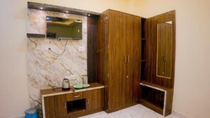 A room with a built-in TV, wooden wardrobe, and a marble wall. - Shiv Darshan P Guest House (Varanasi)
