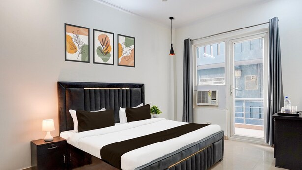 Une chambre moderne avec un grand lit, une table de chevet avec une lampe et une vue sur l’extérieur grâce à une porte vitrée.