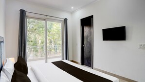 Une chambre d’hôtel avec un lit, un téléviseur fixé au mur et une fenêtre avec des rideaux.