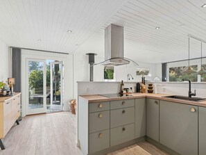 A modern kitchen with a large island, a built-in oven, and a window overlooking a garden. - 4 Star Holiday Home in Hemmet (Hemmet)