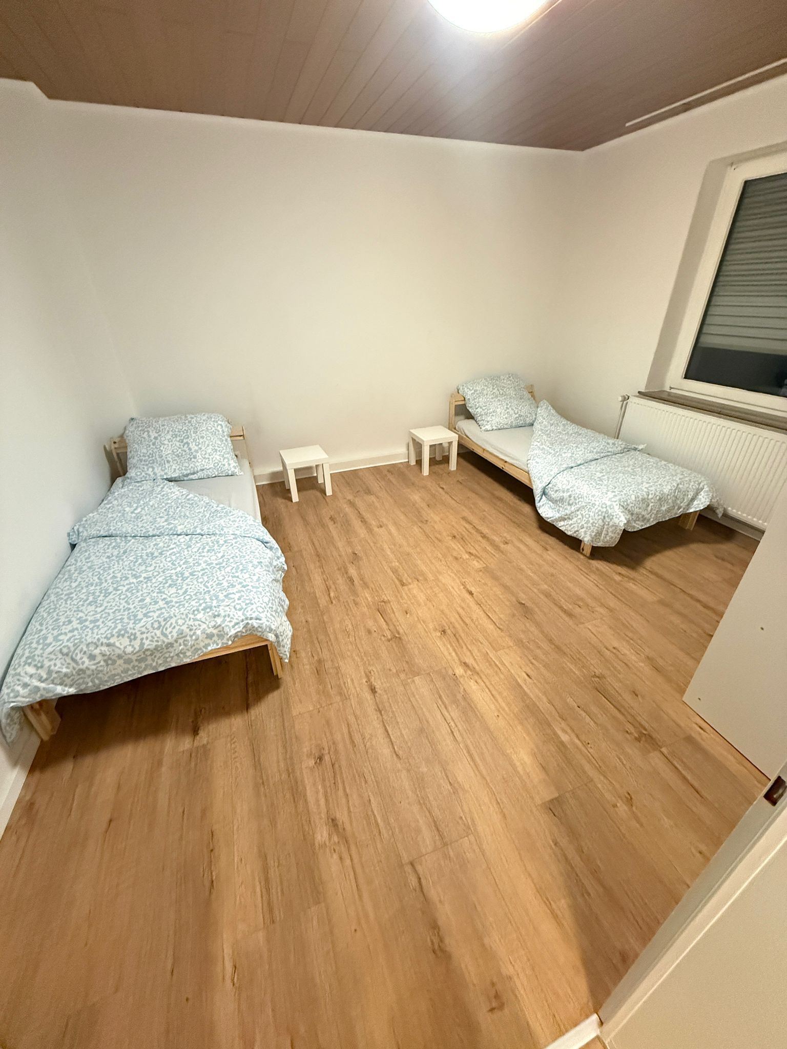 Een kamer met twee bedden, een raam en een radiator.
