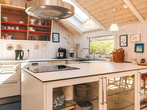 A modern kitchen with a central island, built-in shelves, and a skylight. - 4 Star Holiday Home in Graested (Graested)