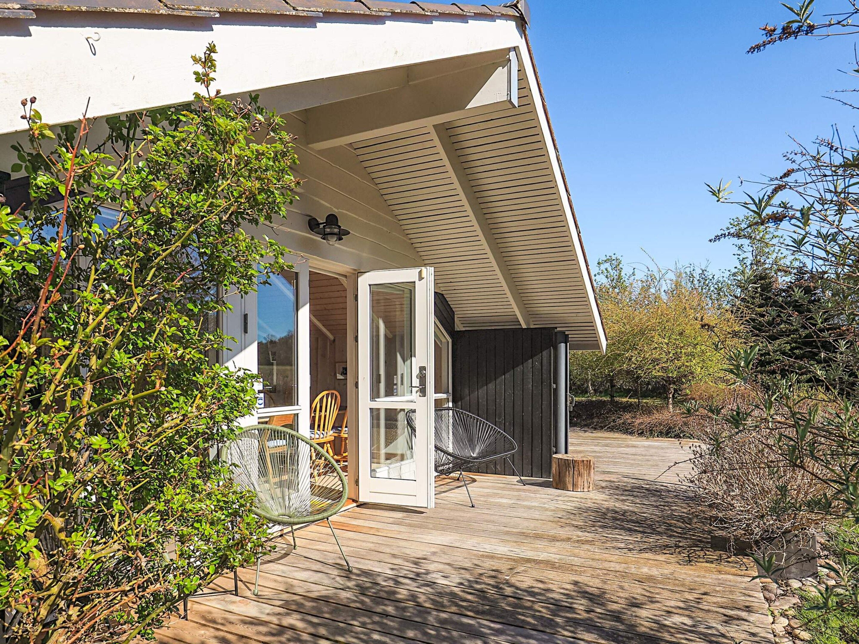 A wooden deck leading to a house with a white exterior and a glass door.