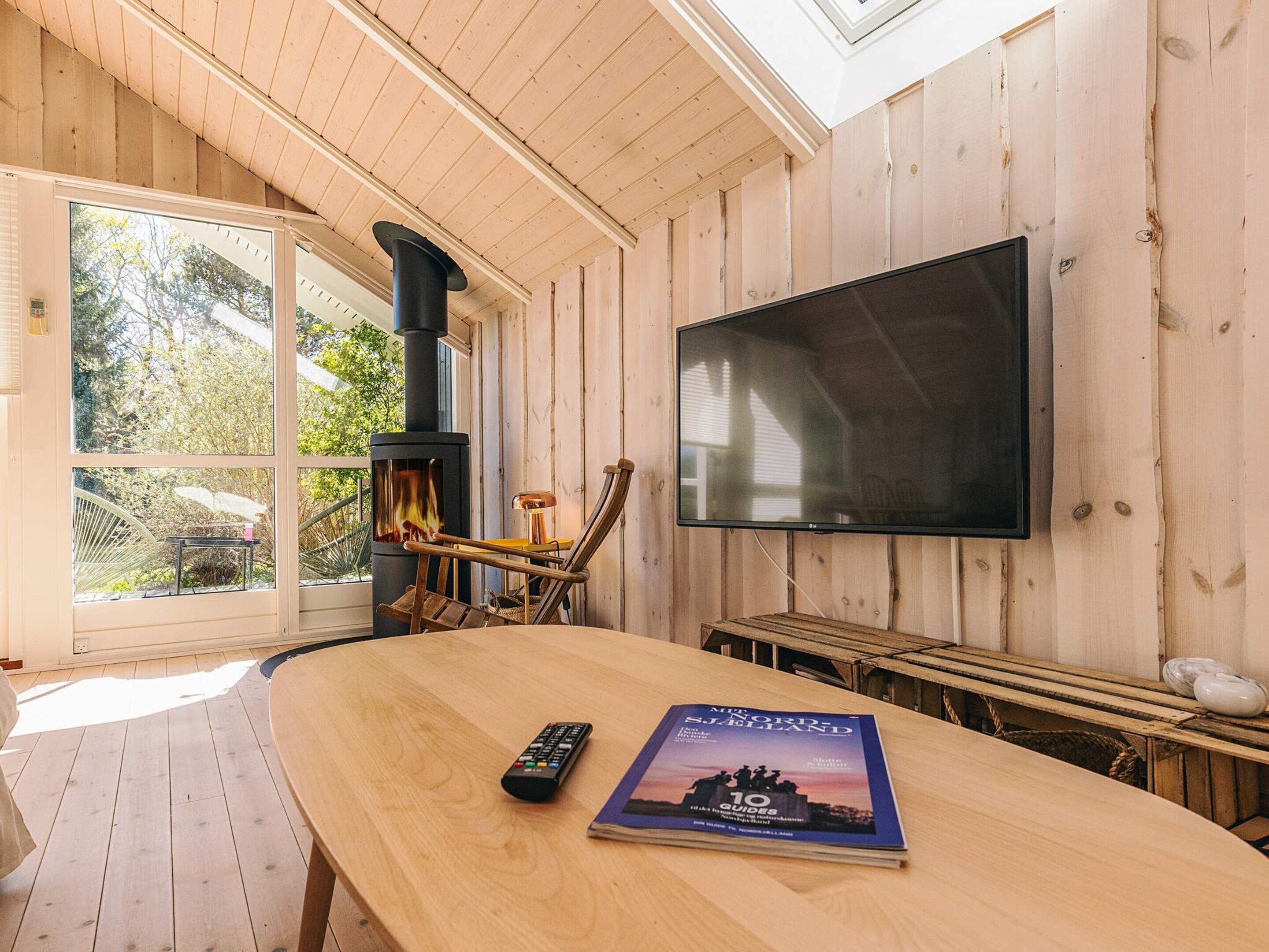 Ein Holzinnenraum mit Kamin, Fernseher und Fernbedienung auf einem Tisch.