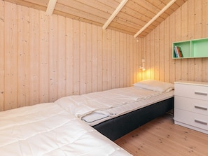 A single bed with a white mattress and a black headboard in a room with wooden walls and a sloped ceiling. - 4 Star Holiday Home in Graested (Graested)