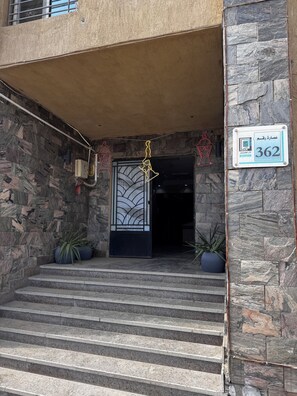 Entrada d'un edifici amb parets de pedra, una porta metàl·lica i un senyal amb el número 362.
