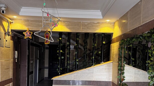 Rebost d'hotel amb sòl de marbre, taulell de recepció, escala i elements decoratius penjants.