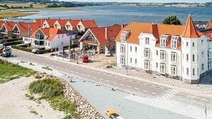 A coastal hotel with red-roofed buildings, a paved road, and a view of the sea. - 4 Star Holiday Home in Hejls (Hejls)