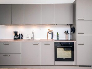 A modern kitchen with grey cabinets, a coffee maker, a toaster, a sink, and an oven. - 4 Star Holiday Home in Hejls (Hejls)