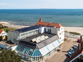 A coastal building with a large glass facade, a sloped roof, and a view of the sea.