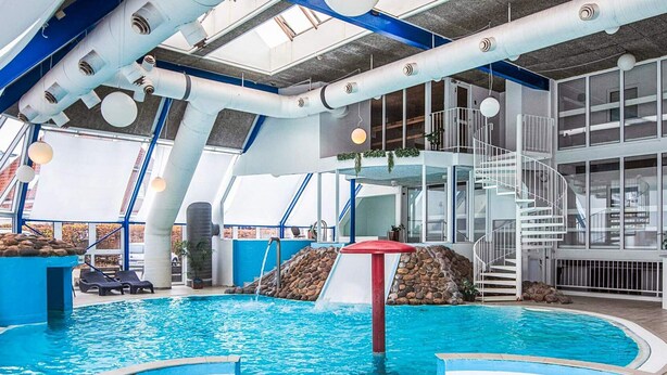 An indoor swimming pool with a slide, a staircase, and lounge chairs. - 4 Star Holiday Home in Hejls (Hejls)