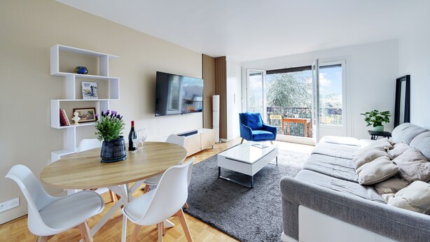 Ein modernes Wohnzimmer mit Essbereich, einer Couch, einem Fernseher und einem Balkon mit Blick.