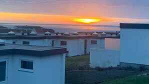 A residential area with multiple white buildings, some with flat roofs and others with pitched roofs, under a sunset sky. - 4 Star Holiday Home in Tranekaer (Tranekaer)