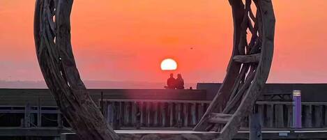 A heart-shaped wooden structure with a sunset in the background.