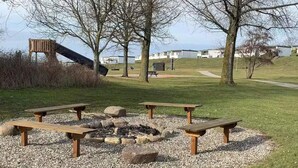 A park with picnic tables, a fire pit, and a playground. - 4 Star Holiday Home in Tranekaer (Tranekaer)