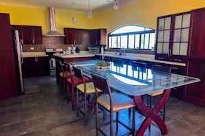 A kitchen with a central island, dark wooden cabinets, a microwave, and a large window.